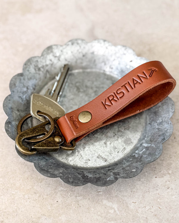 HOOK nyckelring i cognacfärgat läder graverad med "KRISTIAN" med flygplanssymbol, med nyckel i en metallskål