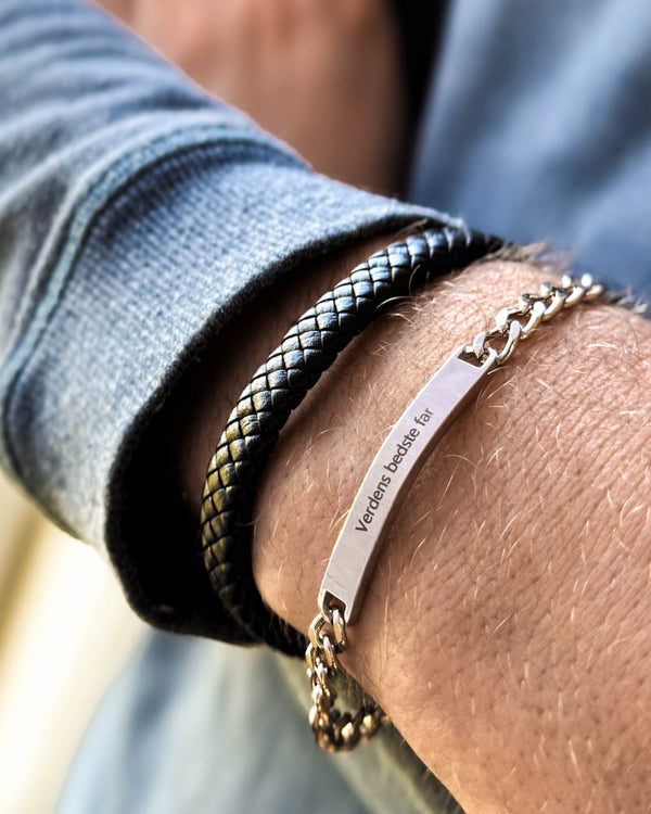 ARA armband i silverfärgat rostfritt stål med gravyren "Verdens bedste far" runt handleden, buret tillsammans med RAY flätat läderarmband