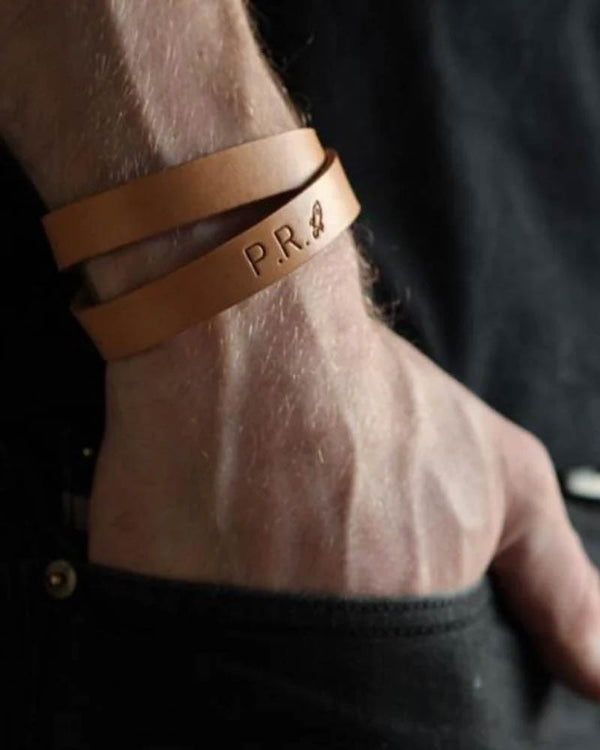 DUO läderarmband, här visat i ljust cognacfärgat läder, med initialerna "P.R." och litet motiv graverat runt manshandled