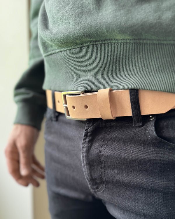 EDGE bälte i naturfärgat läder buret i mörka jeans med grön sweatshirt