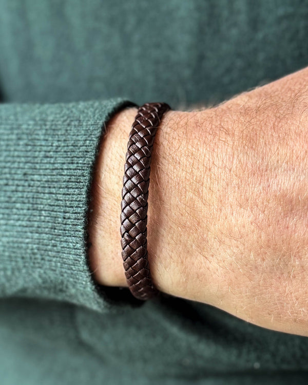 RAY läderarmband i mörkbrunt flätat läder runt en mans handled, mörkgrön stickat