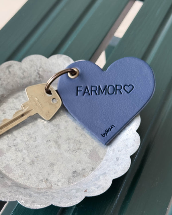 ROSE hjärtnyckelring i mörkblått läder med gravyren "Farmor" ♡ och nyckel i zinkskål på grön träbänk