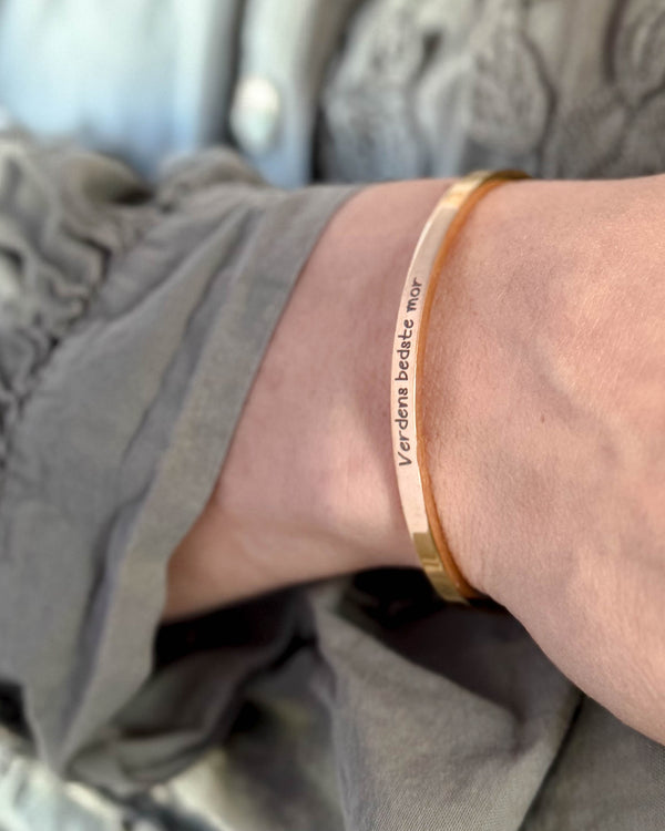 VENUS SCRIPT armband i guldpläterat stål med "Verdens bedste mor" i handskrift runt handleden, grå blus