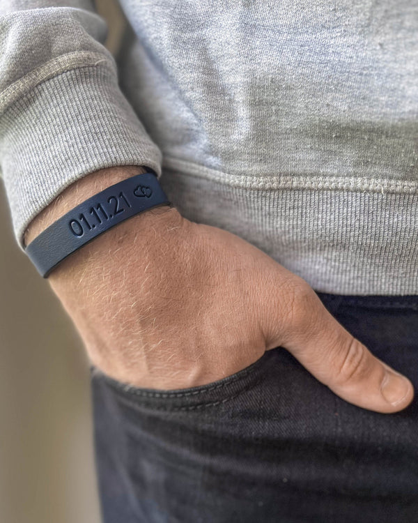 MONO läderarmband i mörkblått läder med datumet "01.11.21" och liten symbol graverat runt handleden, hand i fickan