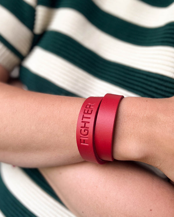 DUO läderarmband i rött läder med gravyren "Fighter" lindat dubbelt runt handleden, grön-vit randig tröja
