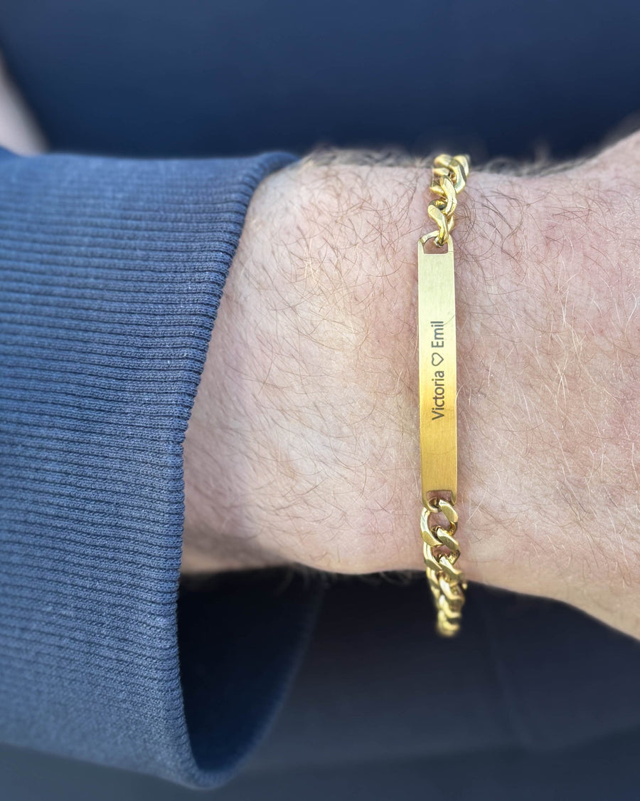 ARA armband i borstat guldpläterat stål med personlig gravyr "Victoria ♡ Emil" runt mannens handled