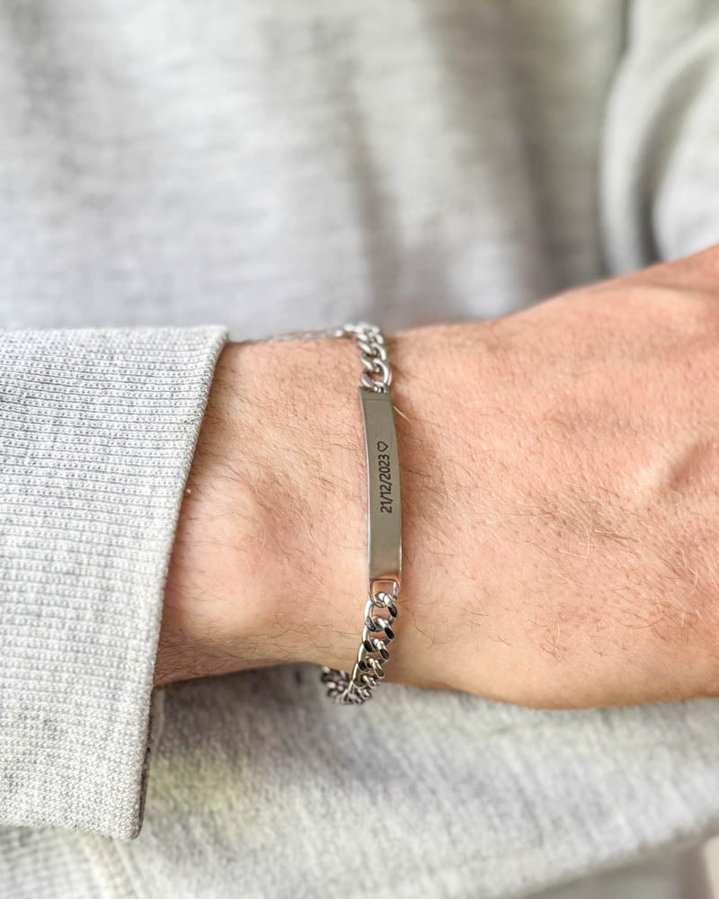 ARA armband i silverfärgat rostfritt stål med datumet "21/12/2023" ♡ graverat, buret runt handleden till ljusgrå sweatshirt