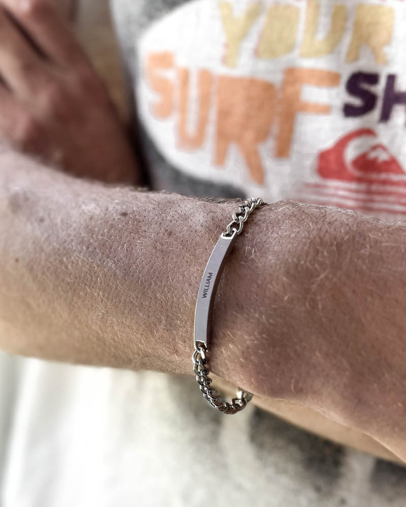 ARA namnarmband i silverfärgat rostfritt stål med namnet "William" graverat, buret runt handleden på stranden