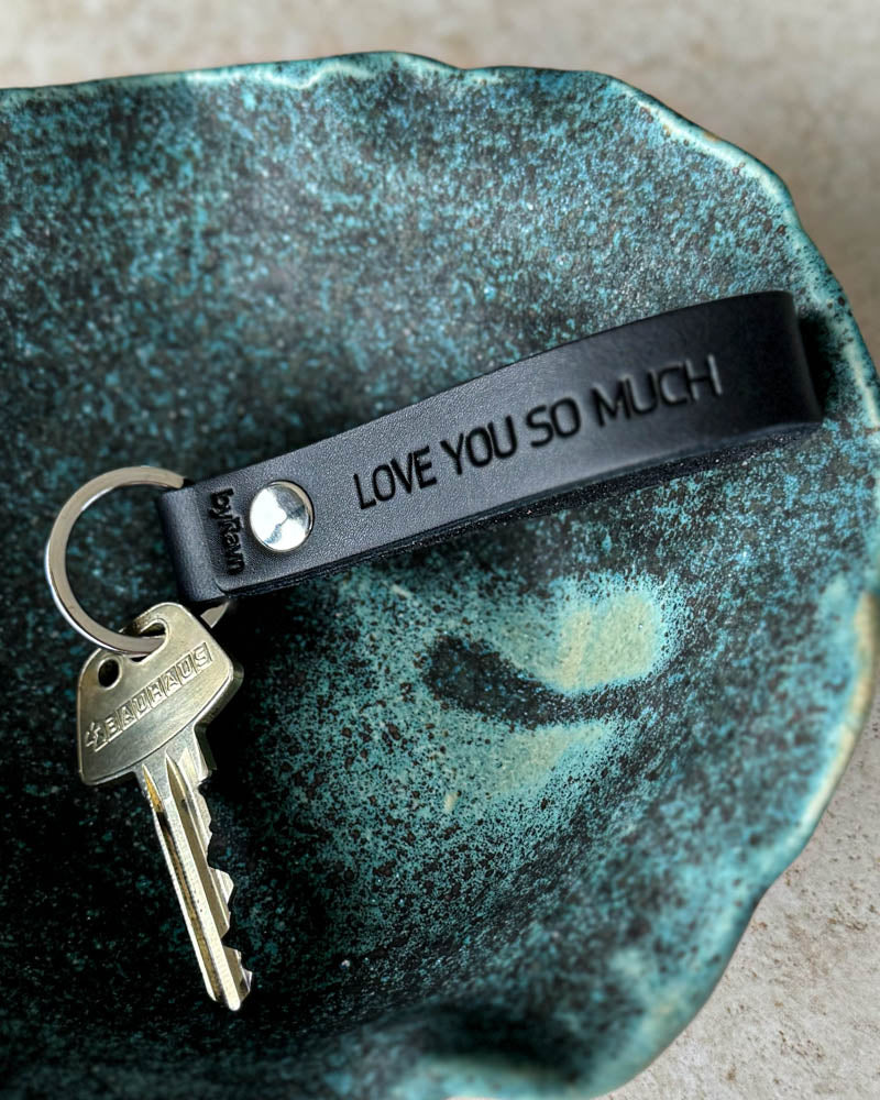 BOND nyckelring i svart läder med personlig gravyr "Love you so much" och nyckel i turkos keramikskål