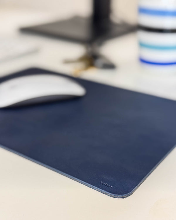 DOS musmatta i mörkblått läder med vit mus på skrivbord vid skärmfot och randig kopp