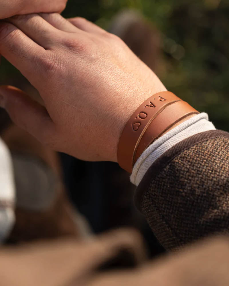 DUO läderarmband i cognac läder med initialerna "P.A.O." ♡ graverade, buret runt handleden utomhus i solsken
