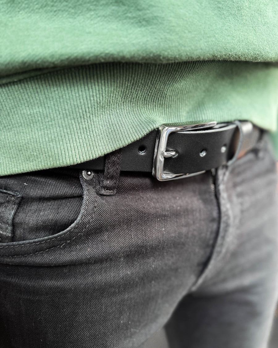 EDGE bälte i svart läder med silverfärgat stålspänne buret i svarta jeans med grön sweatshirt