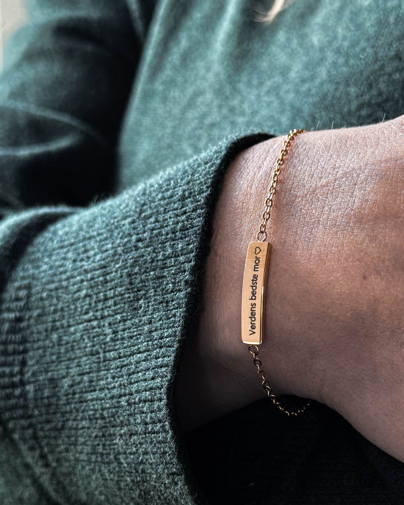 EVI armband i guldpläterat stål med "Verdens bedste mor" ♡ graverat på avlång bricka, buret runt handleden till grön stickat