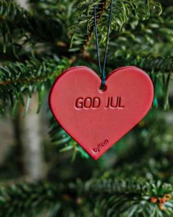FROST julhjärta i rött läder med gravyren "God jul" hängt i grön julgran