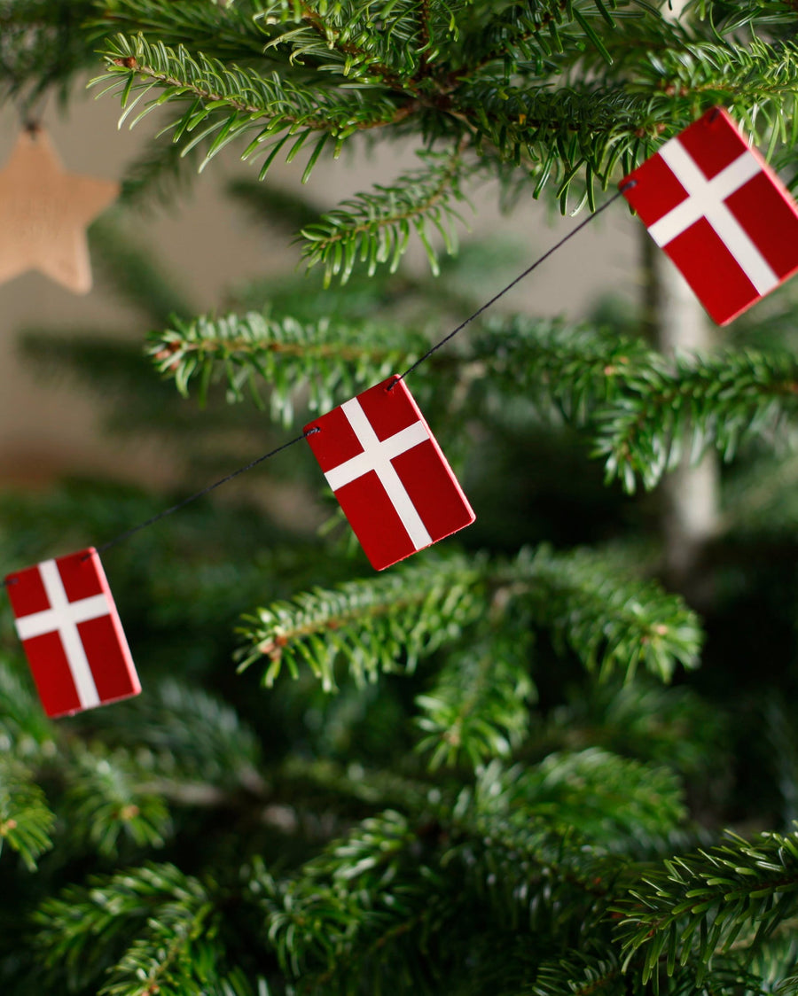 SALUT flaggspel med Dannebrog-flaggor i läder hängt som julpynt i grön julgran med trästjärna