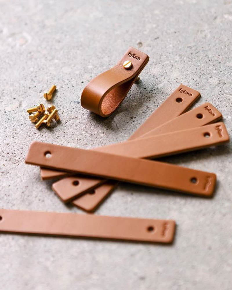 LOOP handtag i cognac läder, flera raka läderremsor med byRavn-prägling, ett monterat handtag och mässingsskruvar