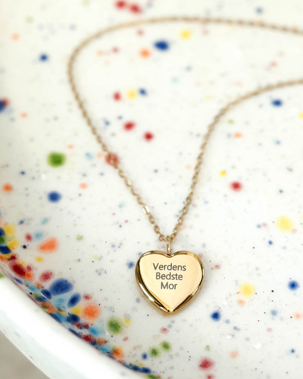LUV QUOTE halsband i guldpläterat stål med gravyren "Verdens Bedste Mor" på hjärthänge, på prickigt keramikfat