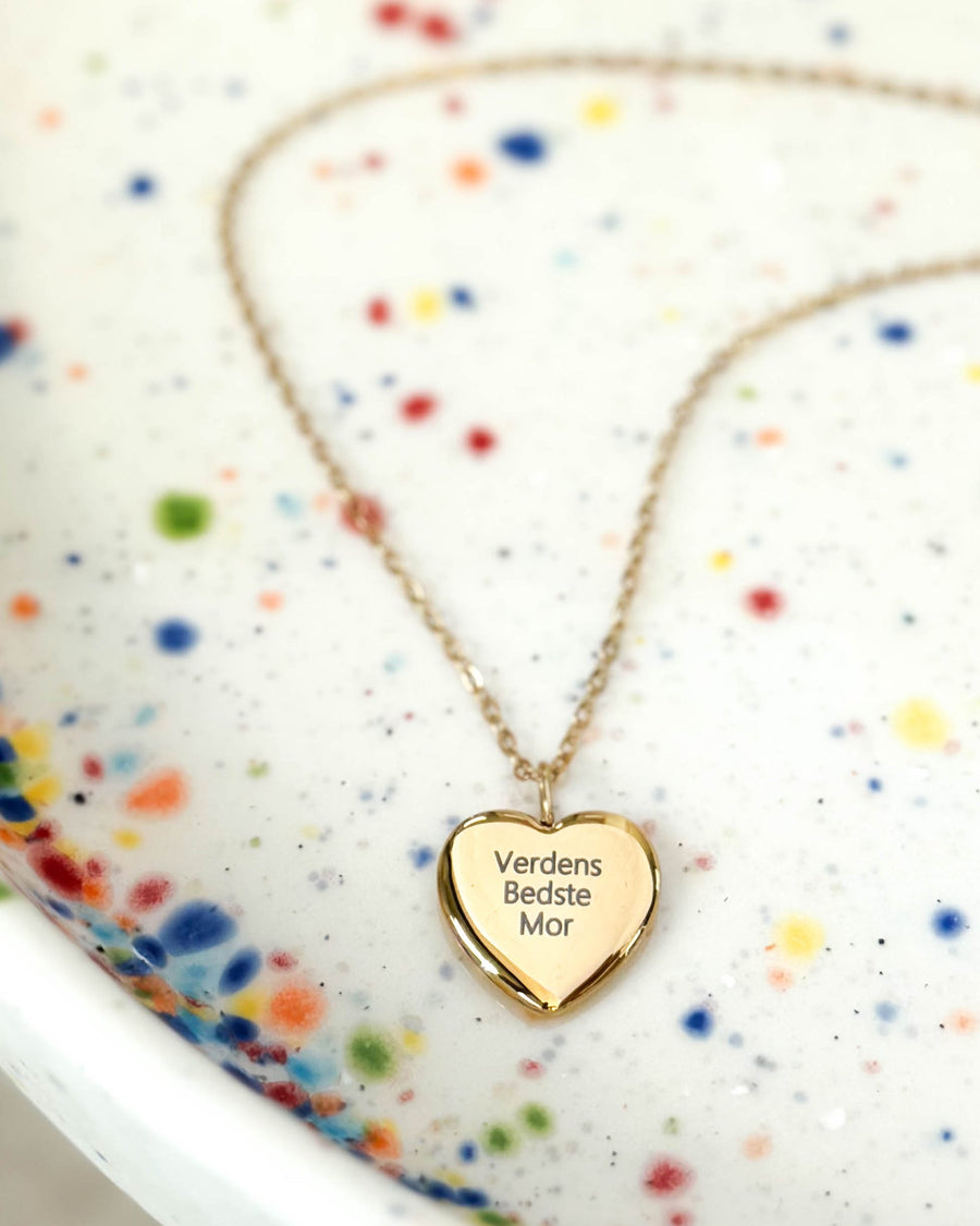 LUV QUOTE halsband i guldpläterat stål med gravyren "Verdens Bedste Mor" på hjärthänge, på prickigt keramikfat