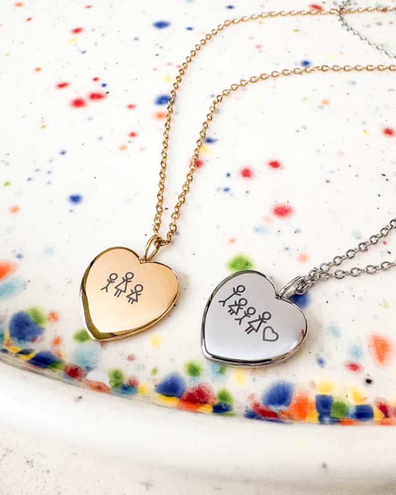 LUV STICK halsband i silverfärgat stål med fyra tändsticksgubbar och hjärta graverat, tillsammans med guldpläterat hjärta på prickigt fat