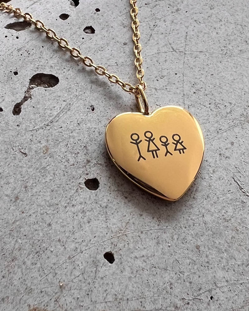 LUV STICK halsband i guldpläterat stål, hjärthänge med tändsticksfamilj på fyra graverad, liggande på rå betong