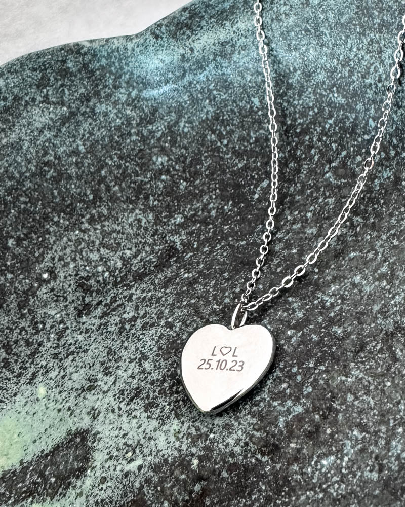 LUV QUOTE halsband i silverfärgat rostfritt stål med personlig gravyr "L ♡ L 25.10.23" på hjärthänge, på grönpatinerad sten