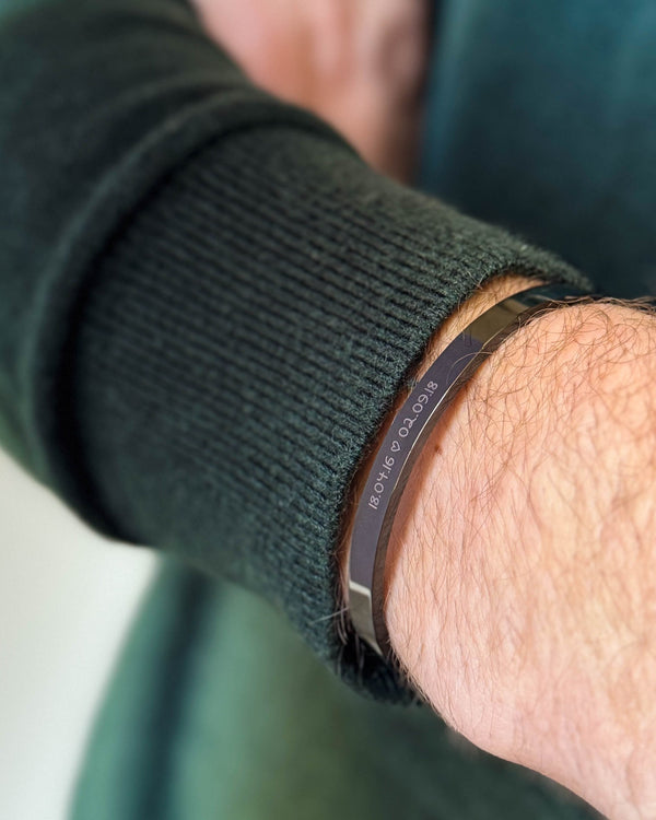 MARS SCRIPT armband i svart stål med datumen "18.04.16 ♡ 02.09.18" graverade i handstil, buret till mörkgrön stickat