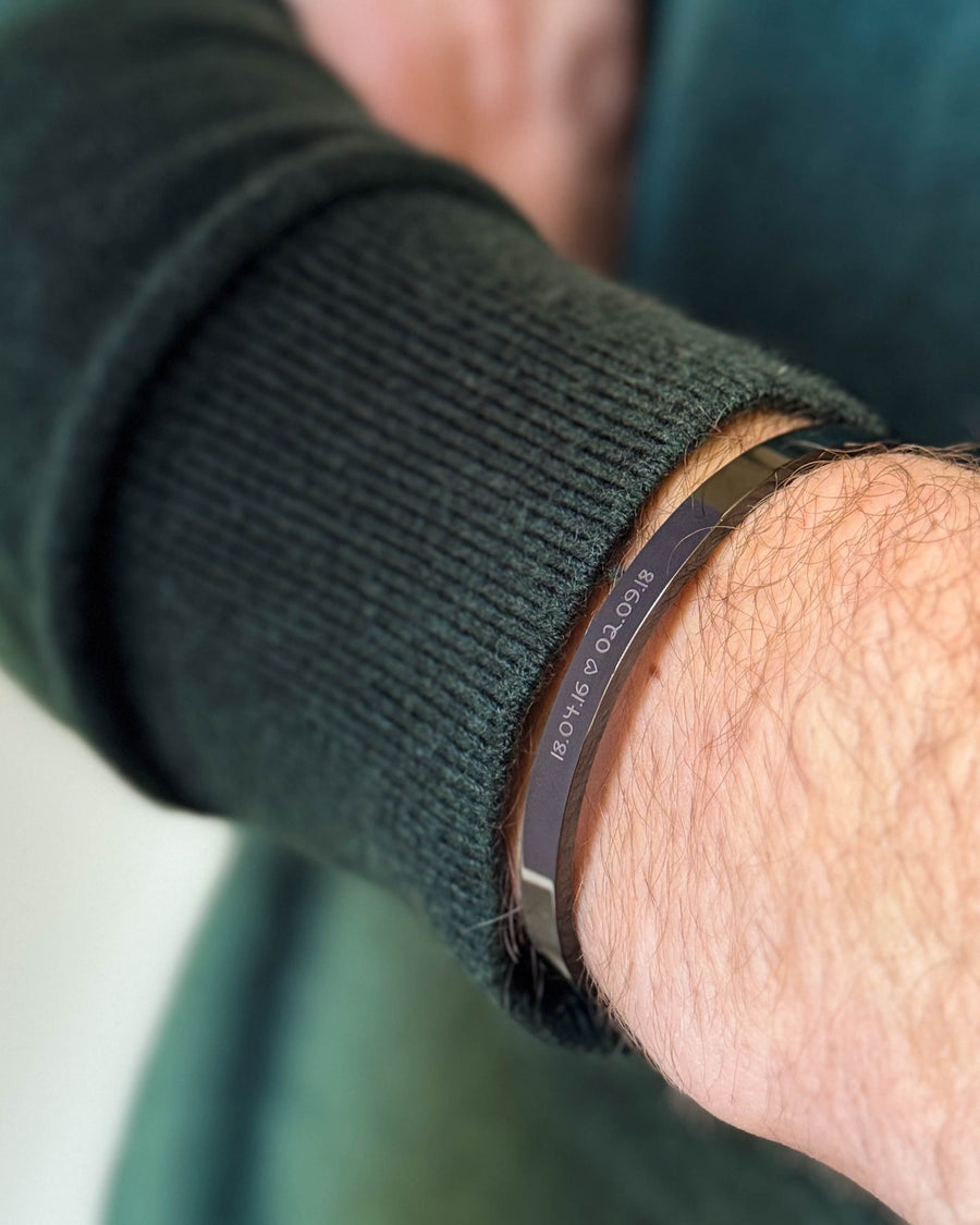 MARS SCRIPT armband i svart stål med datumen "18.04.16 ♡ 02.09.18" graverade i handstil, buret till mörkgrön stickat