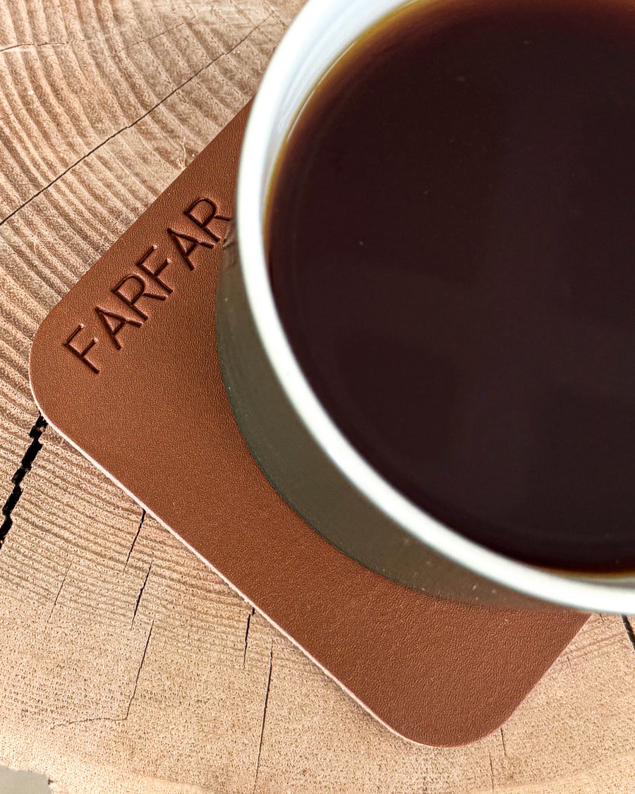 MOKKA fyrkantigt glasunderlägg i cognac läder med gravyren "Farfar" under kopp med kaffe på träskiva