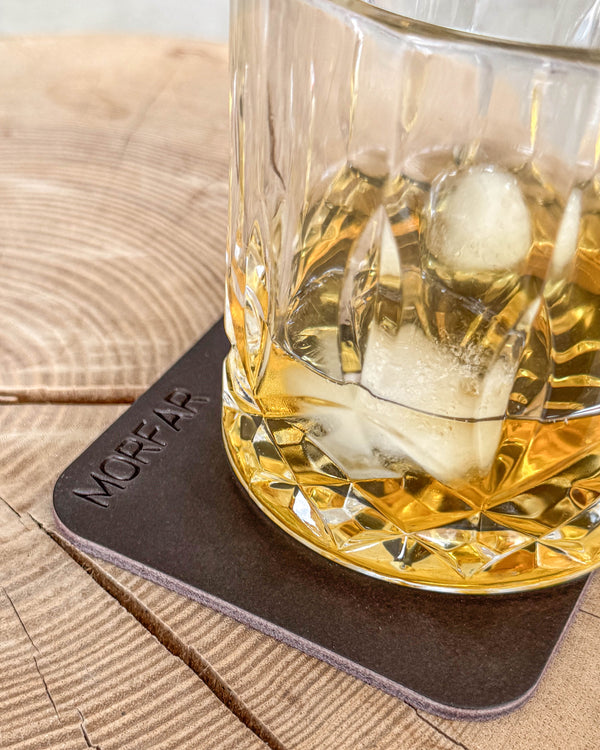 MOKKA fyrkantigt glasunderlägg i mörkbrunt läder med gravyren "Morfar" under kristallglas med whisky och is