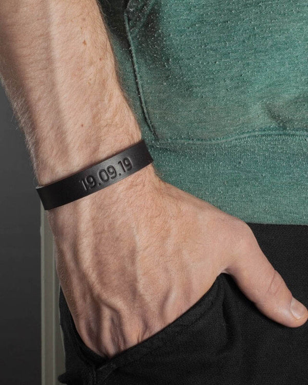 MONO läderarmband i mörkbrunt läder med datumet "19.09.19" graverat runt manshandled, grön t-shirt