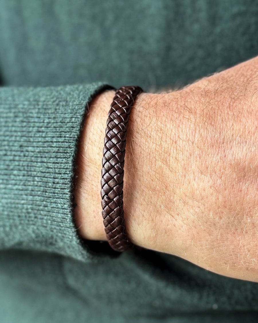 RAY läderarmband i mörkbrunt flätat läder runt en mans handled, mörkgrön stickat