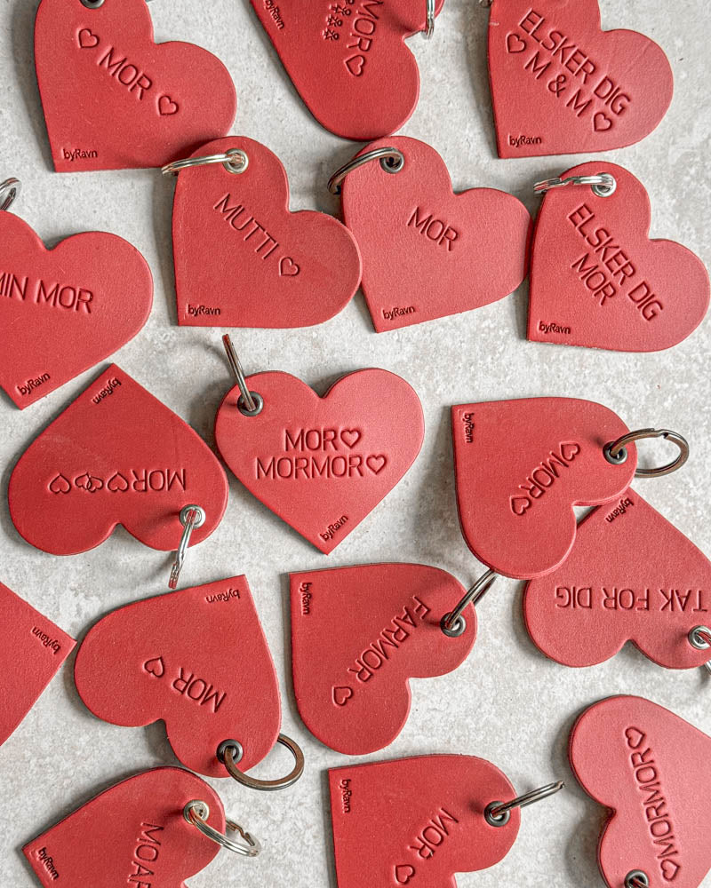 Röda ROSE hjärtnyckelringar i läder sedda ovanifrån med gravyrer som "Elsker dig ♡ M & M ♡", "Min mor" och "Farmor" ♡