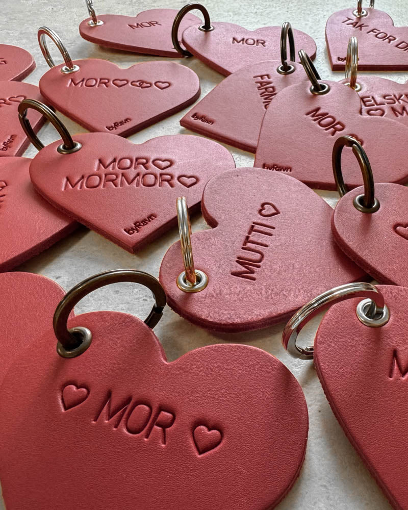 Röda ROSE hjärtnyckelringar i läder i närbild med gravyrerna ♡ "Mor" ♡, "Mutti" ♡ och "Mor ♡ Mormor ♡"