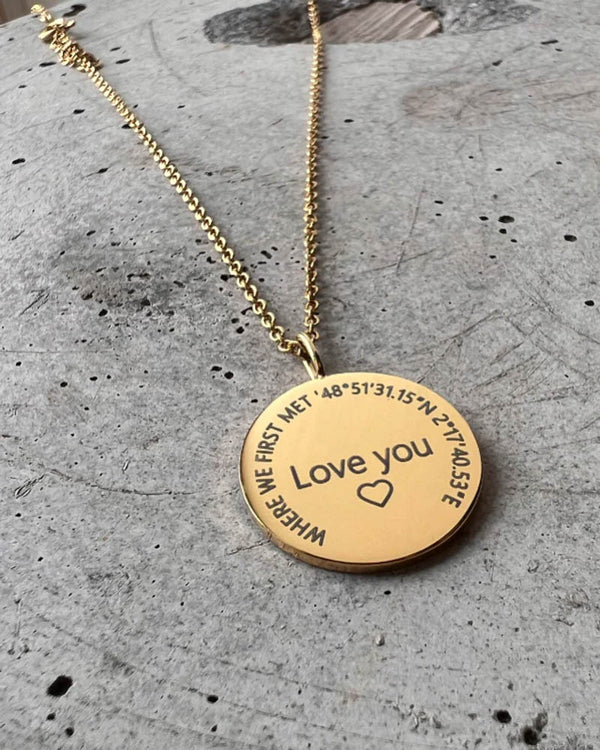 SIA CIRCLE halsband i guldpläterat stål med "Love you" ♡ och "Where we first met" med koordinater graverat i cirkel, på betong