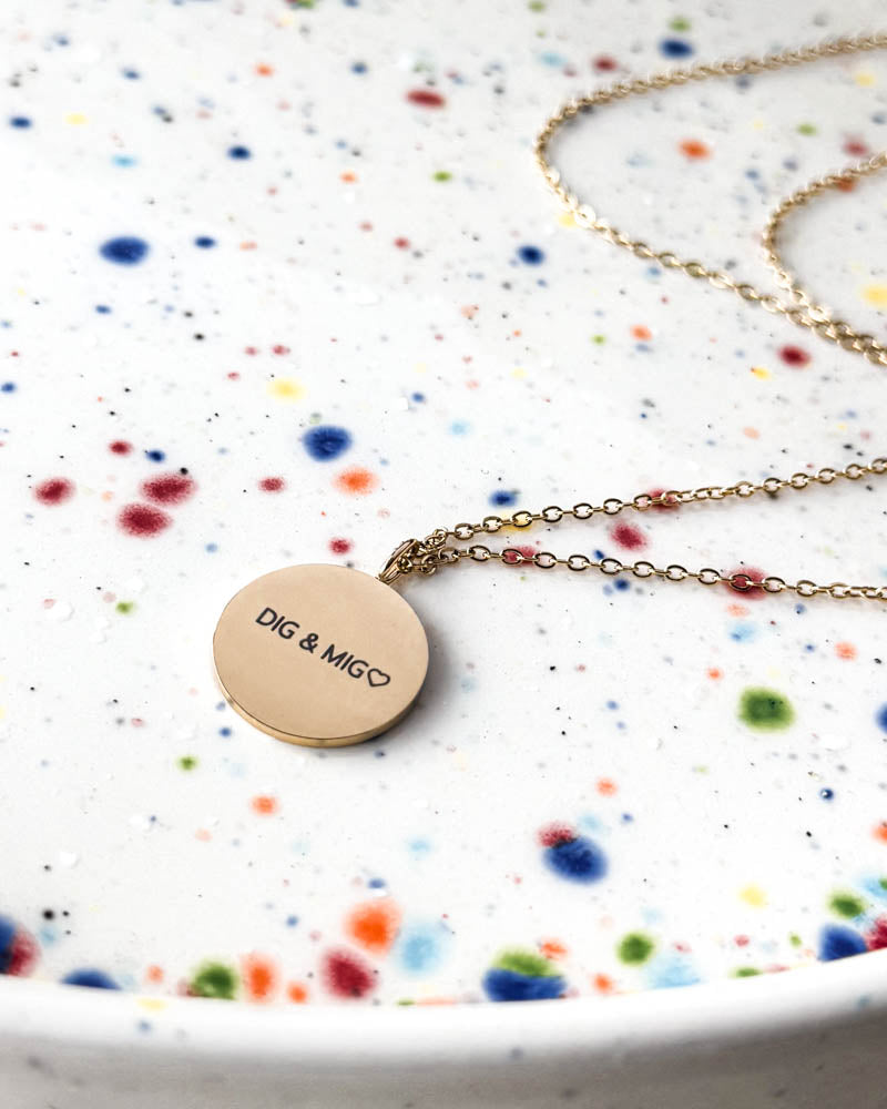 SIA QUOTE halsband i guldpläterat stål med gravyren "Dig & mig" ♡ på runt hänge, på prickigt keramikfat