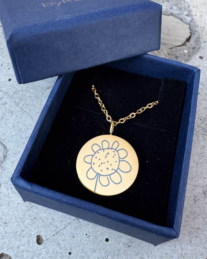 SIA MOTIF halsband i guldpläterat stål med en barnteckning av en blomma graverad, i mörkblå byRavn presentask