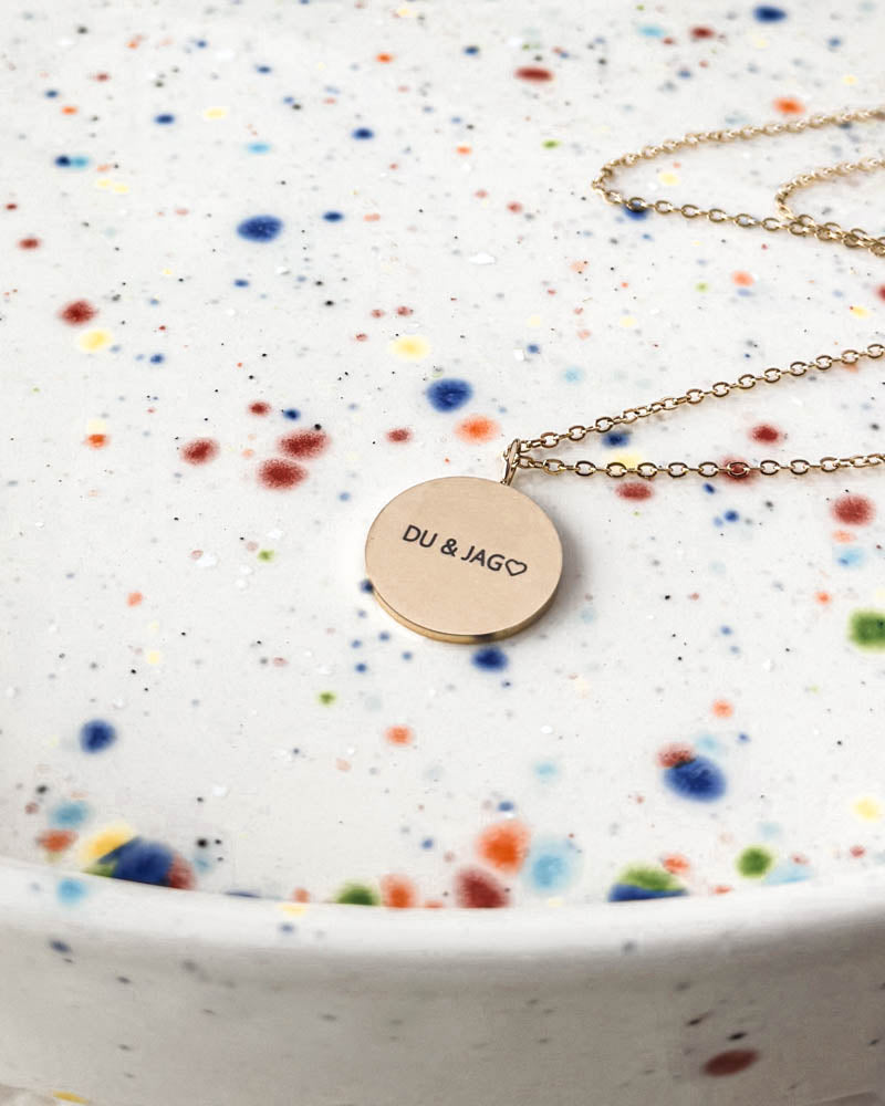 SIA QUOTE halsband i guldpläterat stål med gravyren "Du & jag" ♡ på svenska på runt hänge, på prickigt fat