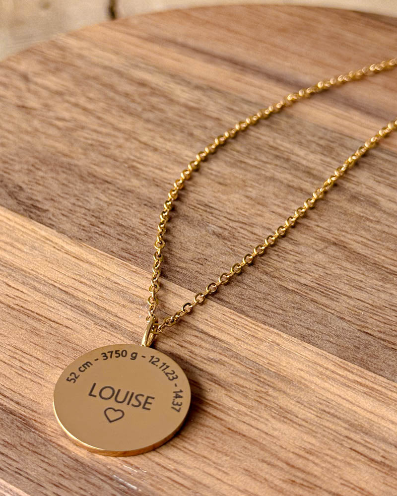 SIA MOMENTS halsband i guldpläterat stål med "Louise" ♡ och födelsedata "52 cm - 3750 g - 12.11.23 - 14.37" graverat, på träfat