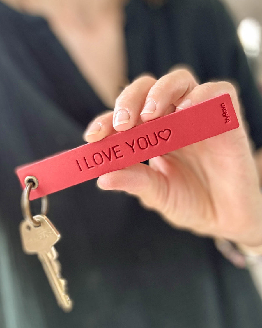 SOLO Large nyckelring i rött läder som hålls fram i handen med nyckel och gravyren "I love you" ♡