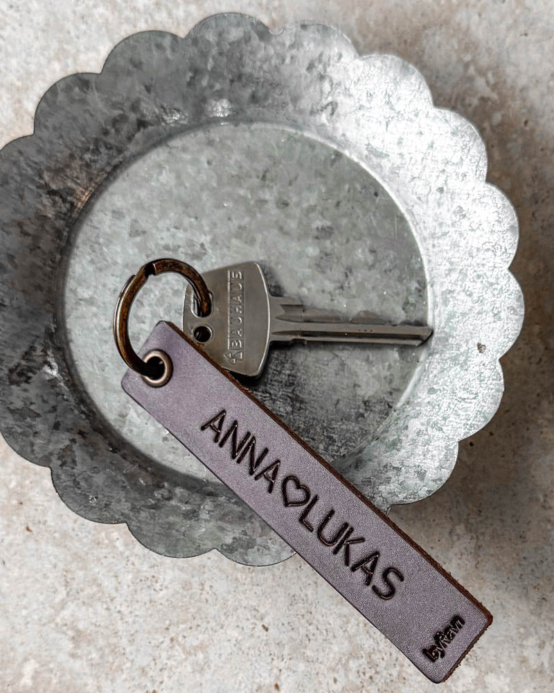 SOLO Medium nyckelring i mörkbrunt läder med personlig gravyr "Anna ♡ Lukas" och nyckel i zinkskål