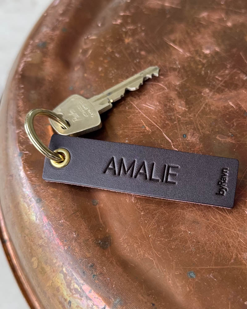 SOLO Small nyckelring i mörkbrunt läder med namnet "Amalie" graverat, gyllene ring och nyckel på kopparbricka