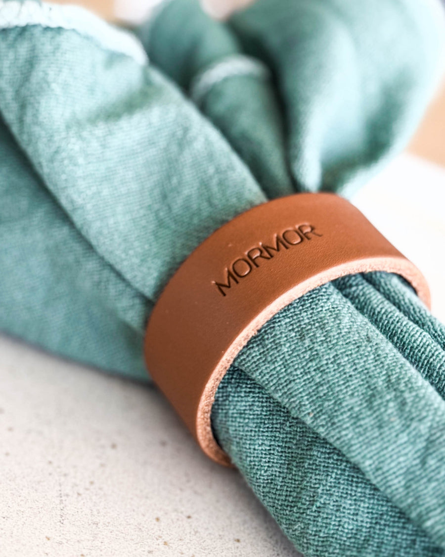 KNOT servettring placeringskort i cognac läder med gravyren "Mormor" runt grön tygservett