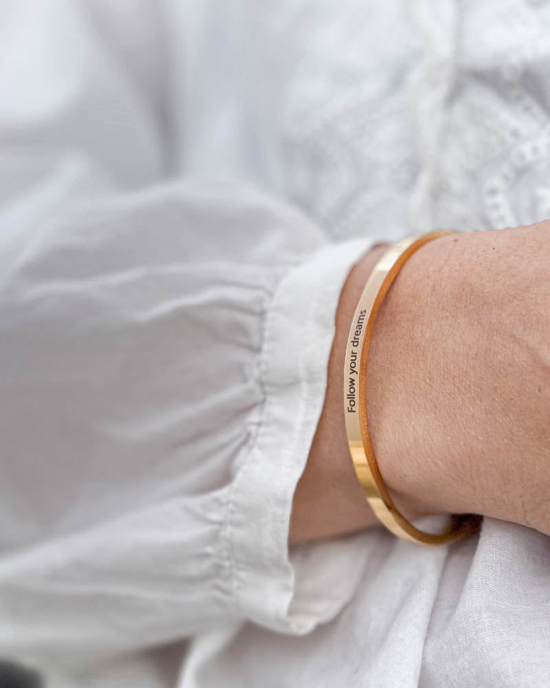 VENUS armband i guldpläterat stål med gravyren "Follow your dreams" till vit blus med puffärmar