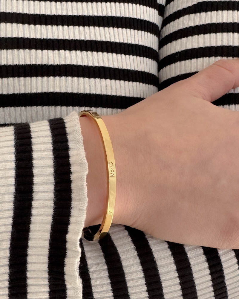VENUS armband i guldpläterat stål med gravyren "Mor" ♡ runt handleden, svart-vit randig stickad tröja